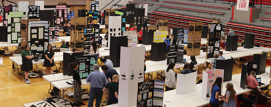 Image of people engaging with the science fair in the gym.