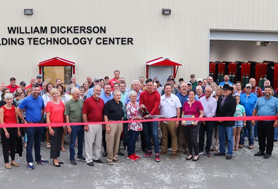 Photo of large group cutting red ribbon in front of William Dickerson Welding Technology Center