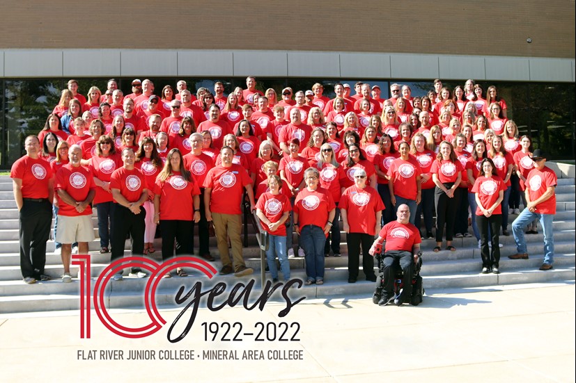 The staff of Mineral Area College wearing red shirts and standing on a set of stairs outside.