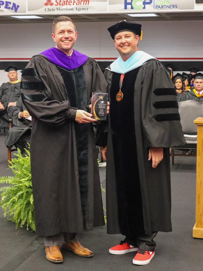 Judge Brice Sechrest accepts the Distinguished Alumni Award from Dr. Joe Gilgour at the 2024 Commencement Ceremony