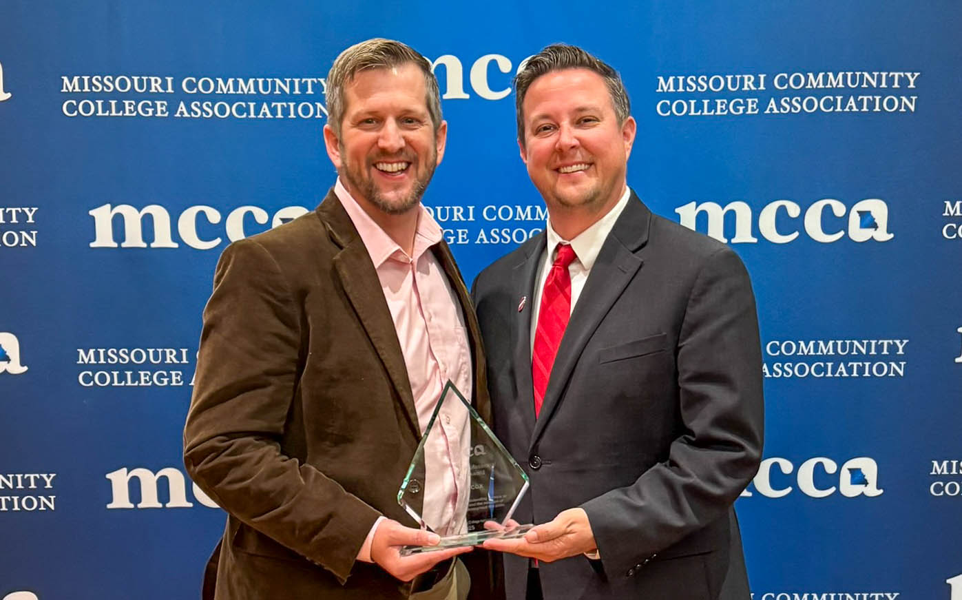Dan Jaycox and Dr. Joe Gilgour holding award in front of MCCA backdrop