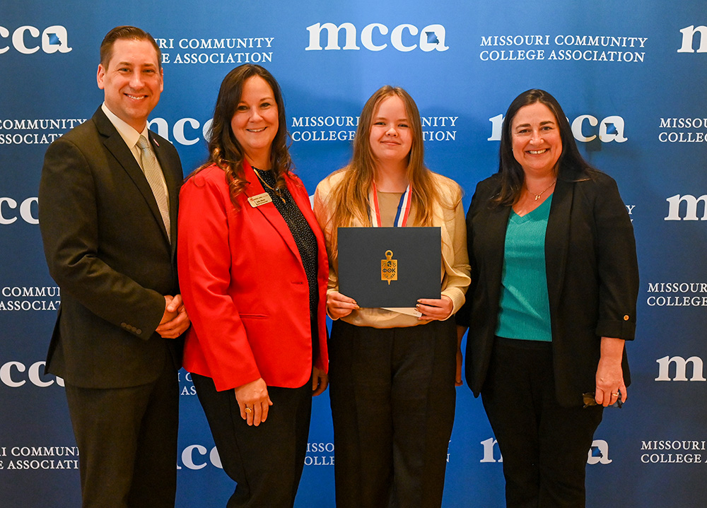 Dr. Keith Zoromski, Dean Julie Sheets, Ashley Edgar, and Alison Sheets in front of MCCA photo backdrop